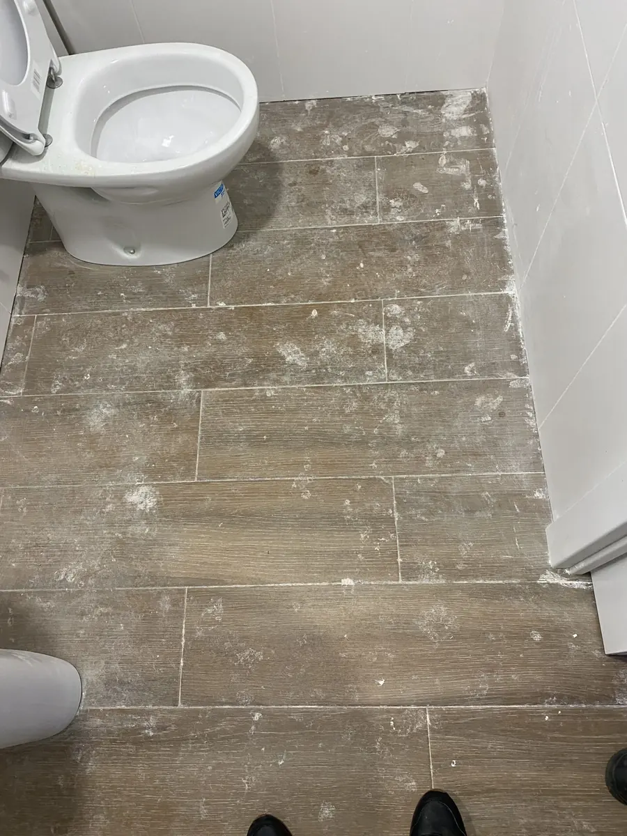 Suelo de baño con restos de obra y polvo antes de la limpieza