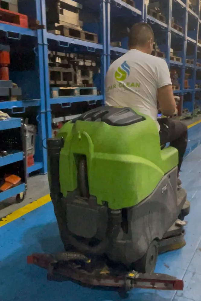 Operario de Ipar Clean con una fregadora industrial en el pasillo de un almacén
